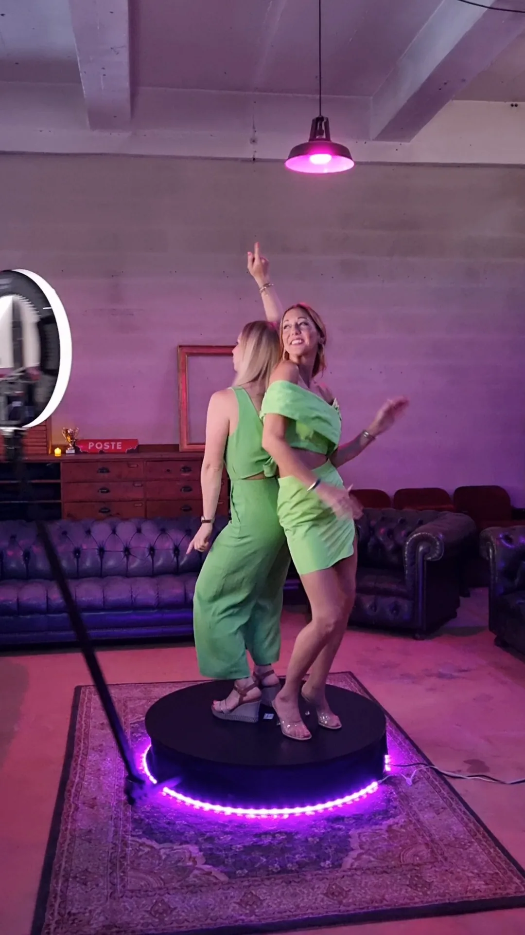 Guest mid-spin on a 360 photo booth platform under magenta lighting