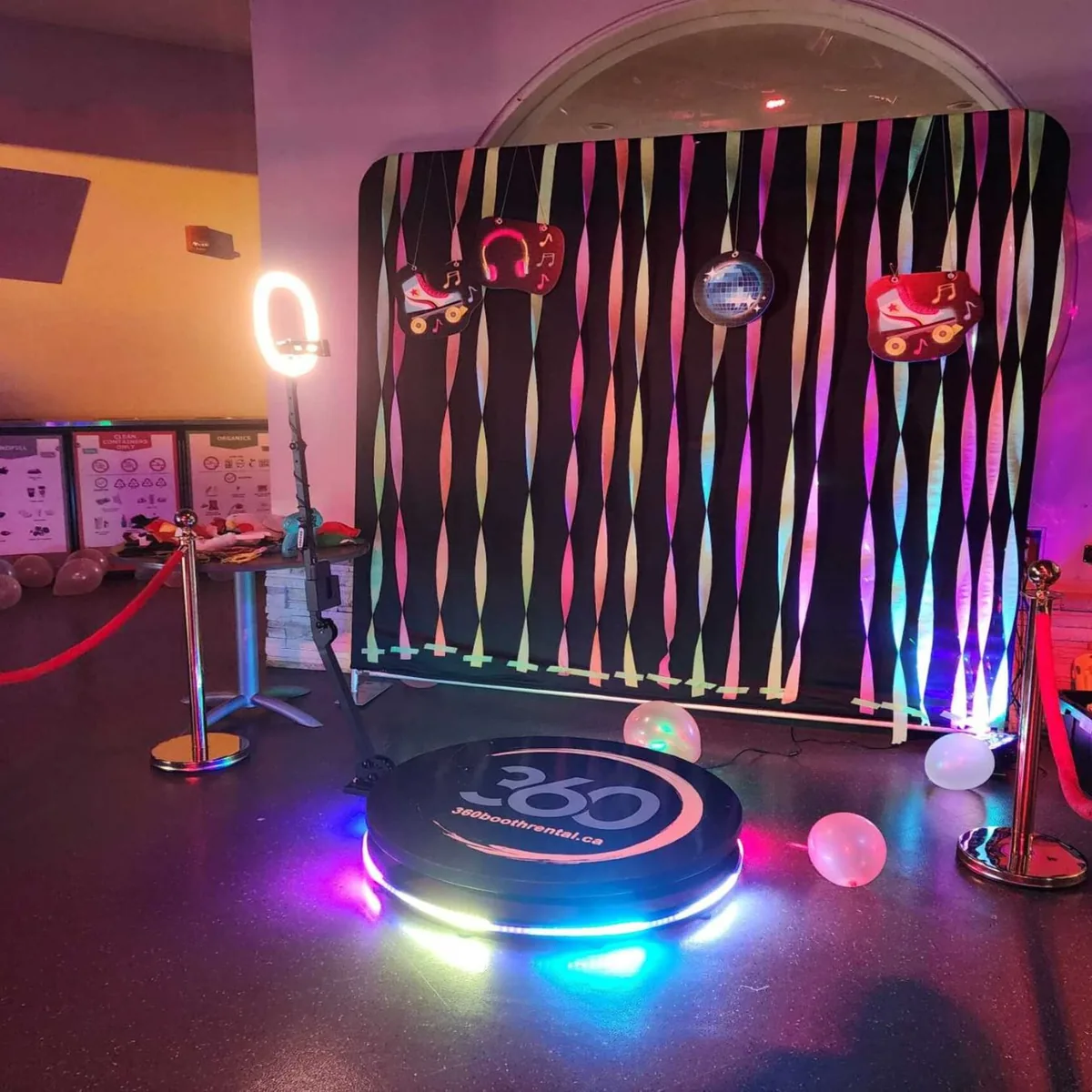 360 video booth with a black streamer backdrop and colored lighting