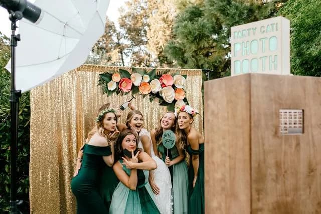 Bridesmaids posing in front of a gold sequin photo booth backdrop at a Chicago wedding