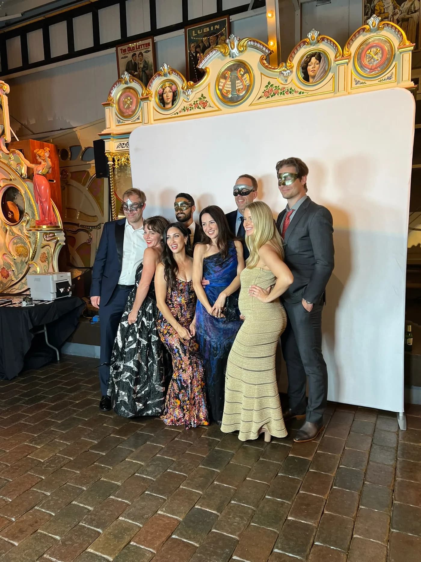 Formally dressed guests posing at an event photo booth with a gold frame