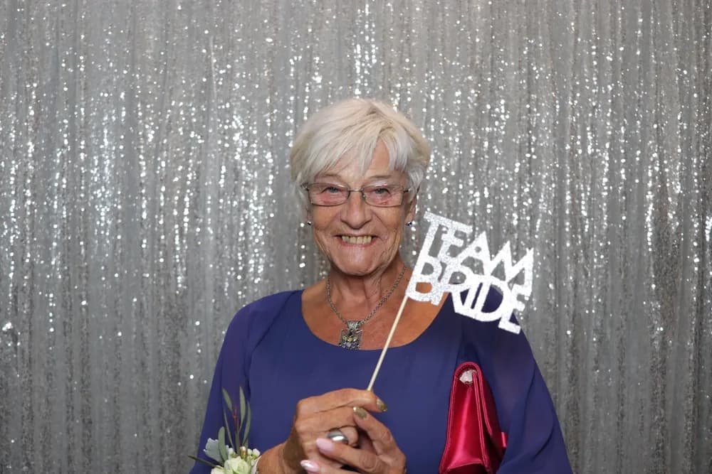 Guest holding a Team Bride prop sign at an open air photo booth