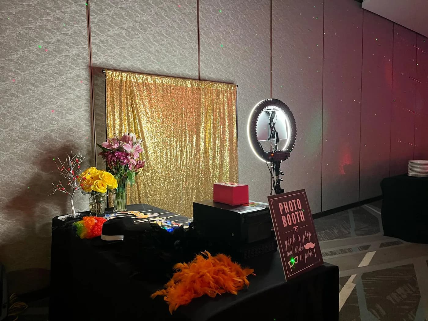 Open air photo booth setup with a gold sequin backdrop and prop table