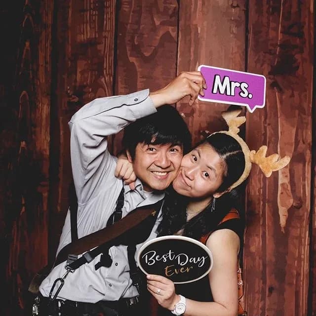 Couple holding a Mrs. prop sign at a wedding photo booth